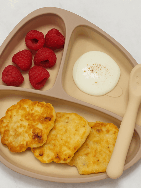 This high protein pancake, known in Ukraine as syrniki, uses cottage cheese to provide a souffle like texture; shown here plated with raspberries and yogurt.