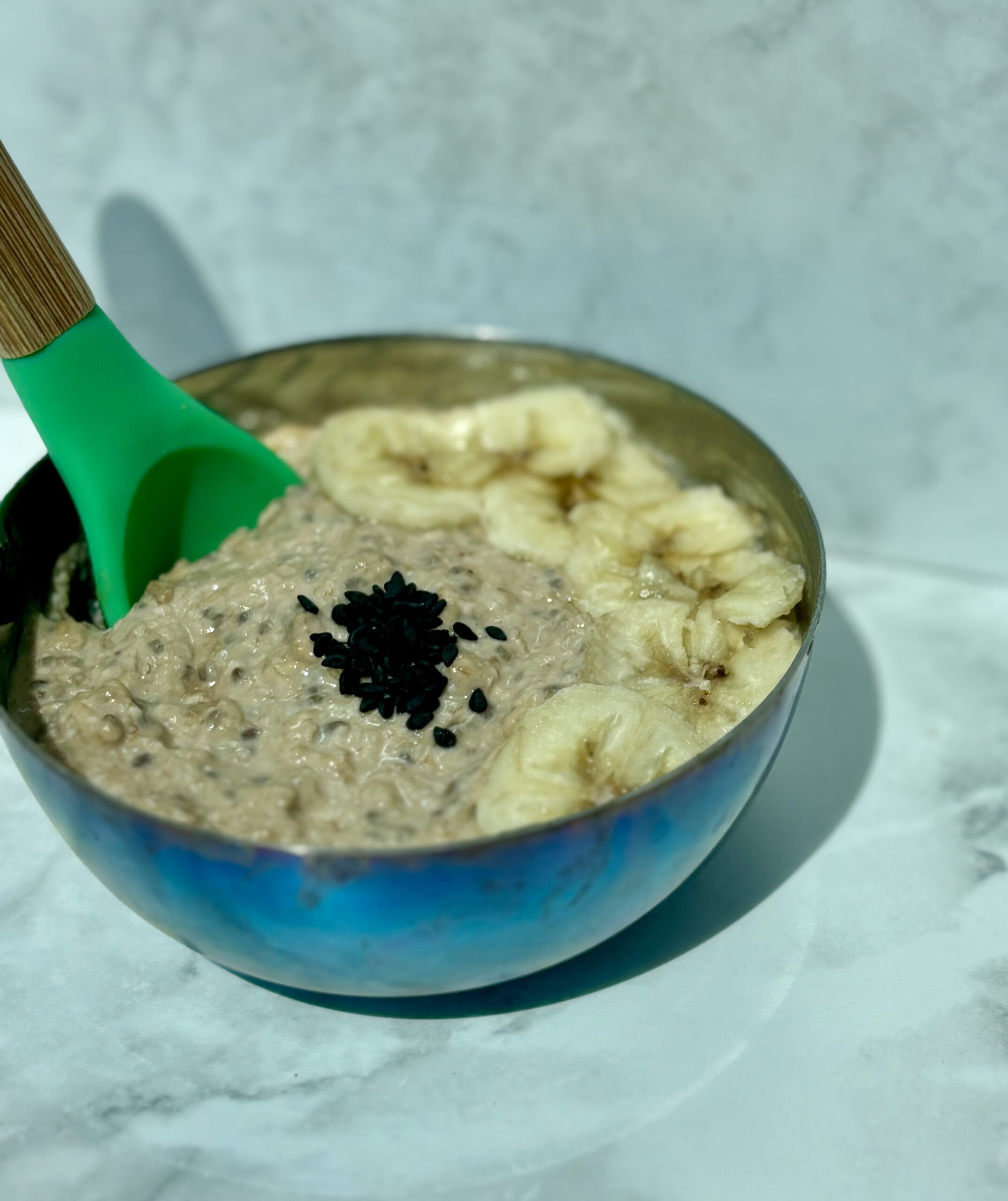 A bowl of quinoa overnight oats and cashew cream that is topped with banana slices and chia seeds