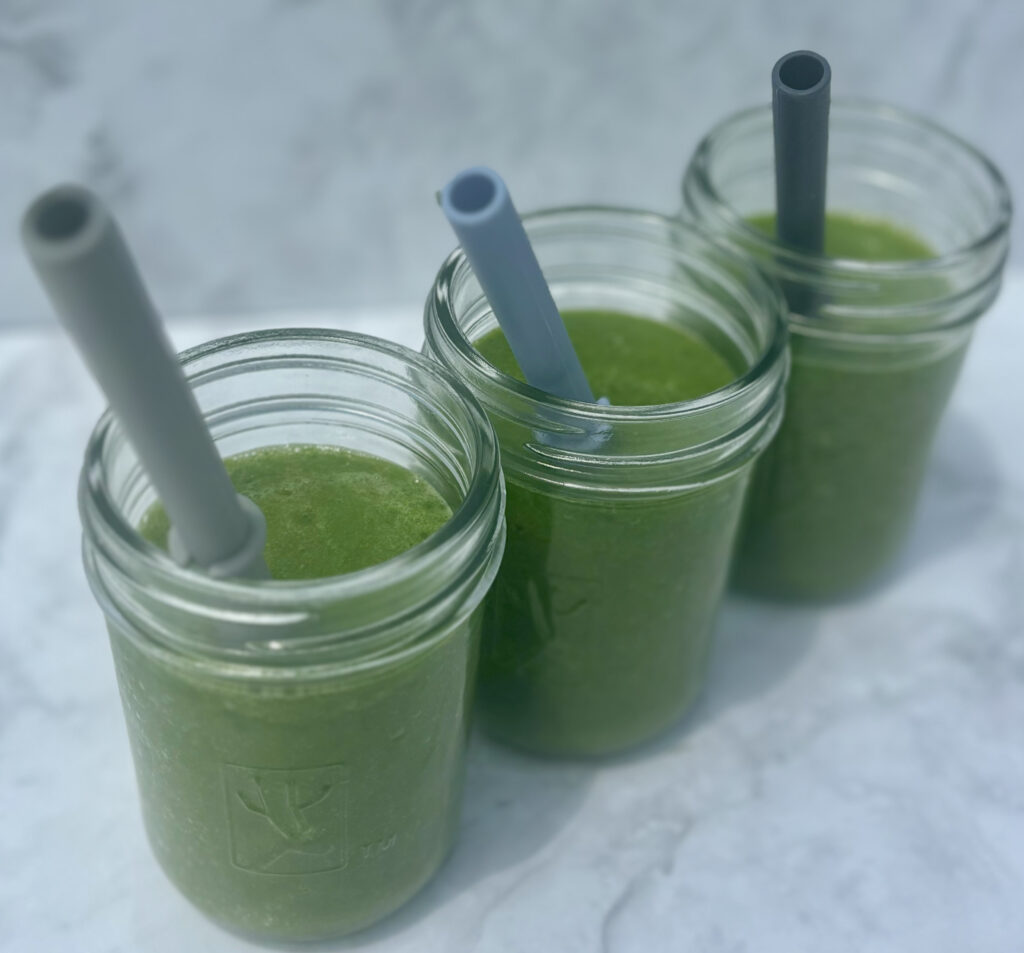 Glasses full of a juice made from spinach, cucumber, mango, lemon, coconut water, and ginger