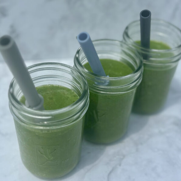 Glasses full of a juice made from spinach, cucumber, mango, lemon, coconut water, and ginger