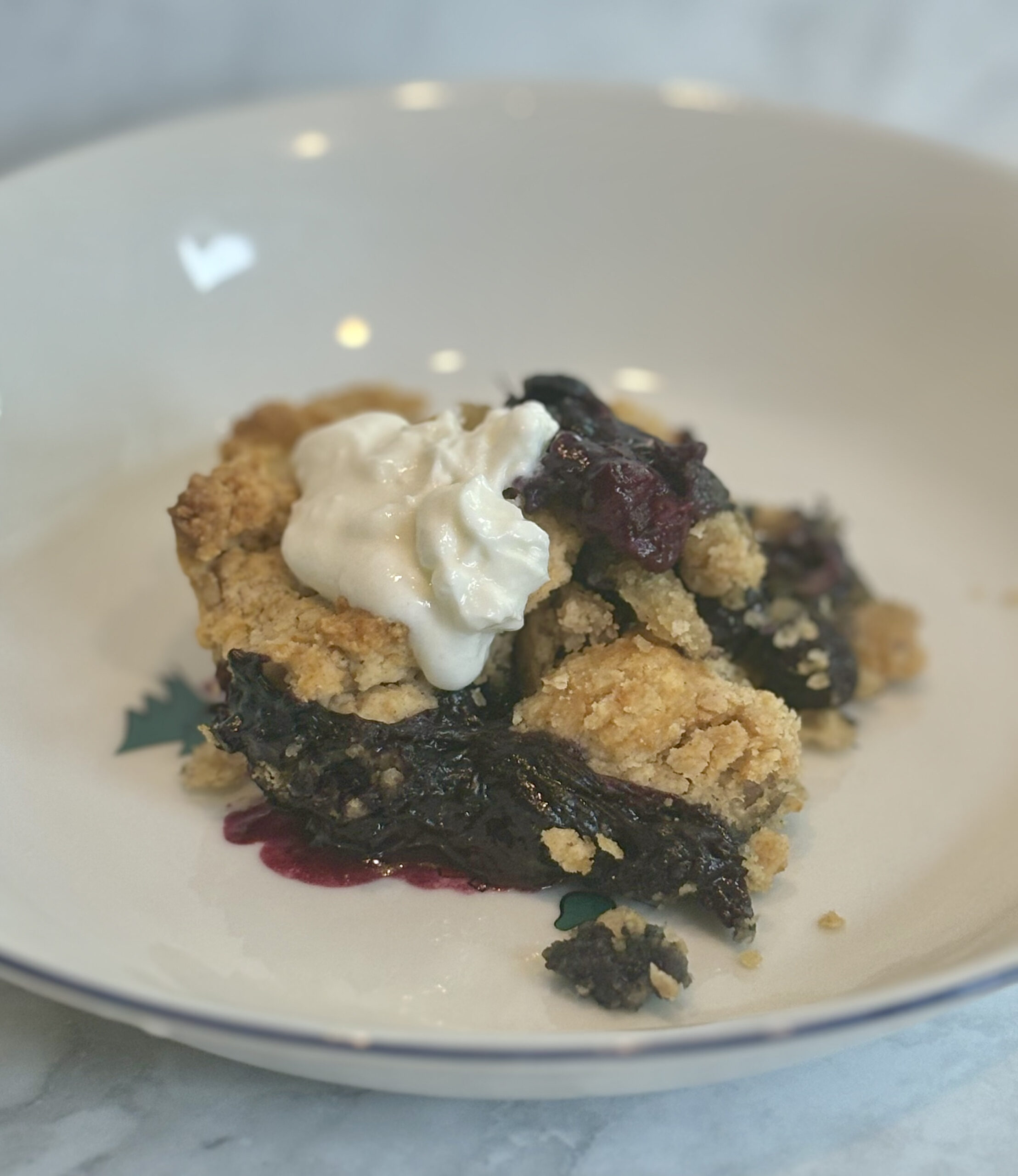 A slice of blueberry cobbler, topped with a dollop of yogurt.