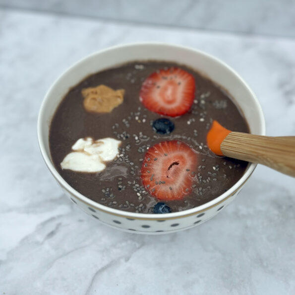 A bowl full of acai, topped with fruit, peanut butter, yogurt, and chia seeds.