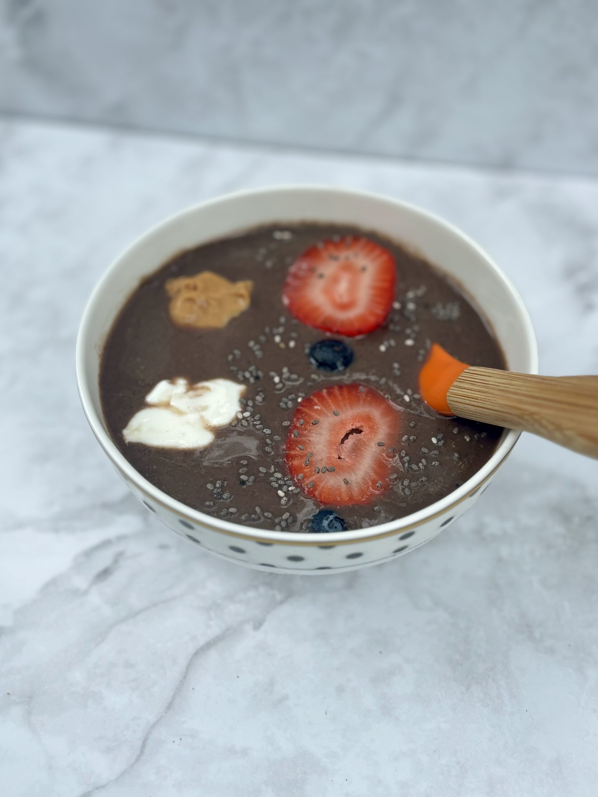 A bowl full of acai, topped with fruit, peanut butter, yogurt, and chia seeds.