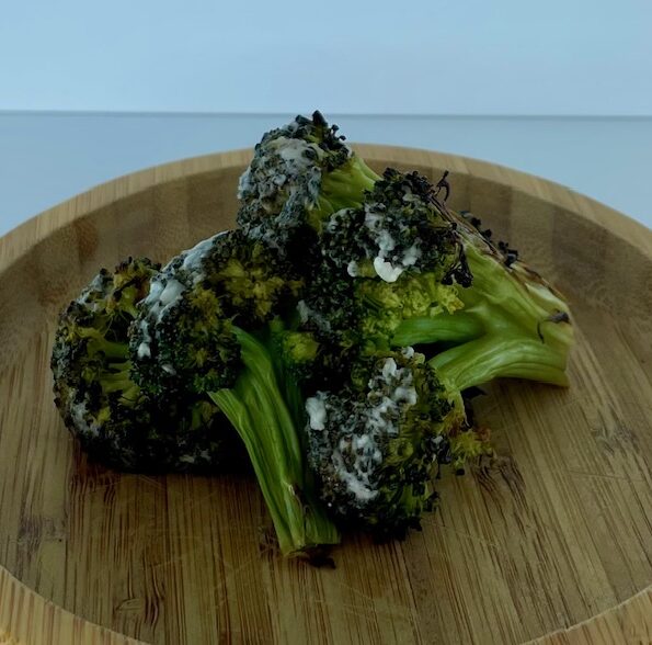 A pile of broccoli florets stacked on a plate.