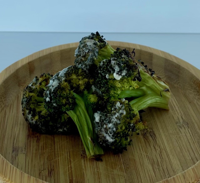 A pile of broccoli florets stacked on a plate.