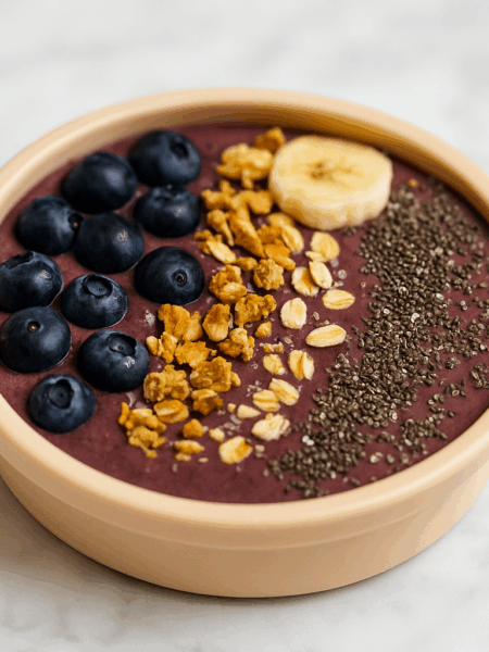 A first acai smoothie bowl for kids is shown topped with berries, nuts, and seeds.