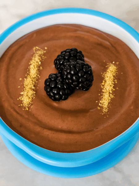 A chocolate peanut butter pudding for toddlers contains tofu and is topped with blackberries and graham cracker crumbs.