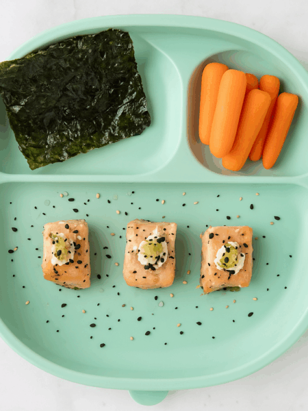 salmon bites for toddlers--flavored like an everything bagel--are shown on a plate with carrots and seaweed.