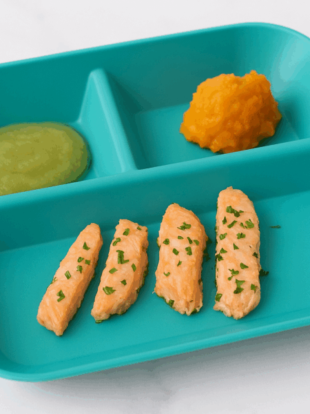 How to introduce salmon to infants: thin slices of softly cooked salmon line a plate that also includes applesauce and sweet potatoes.