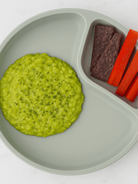 A pool of toddler guacamole is sided by chips and vegetable strips.