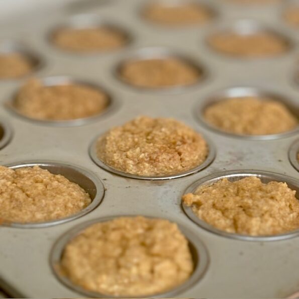 A closeup of apple-sour-cream muffins still in their muffin tray.