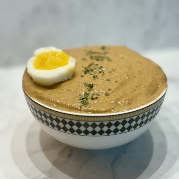 A bowl of gazpacho is topped with a hardboiled egg.