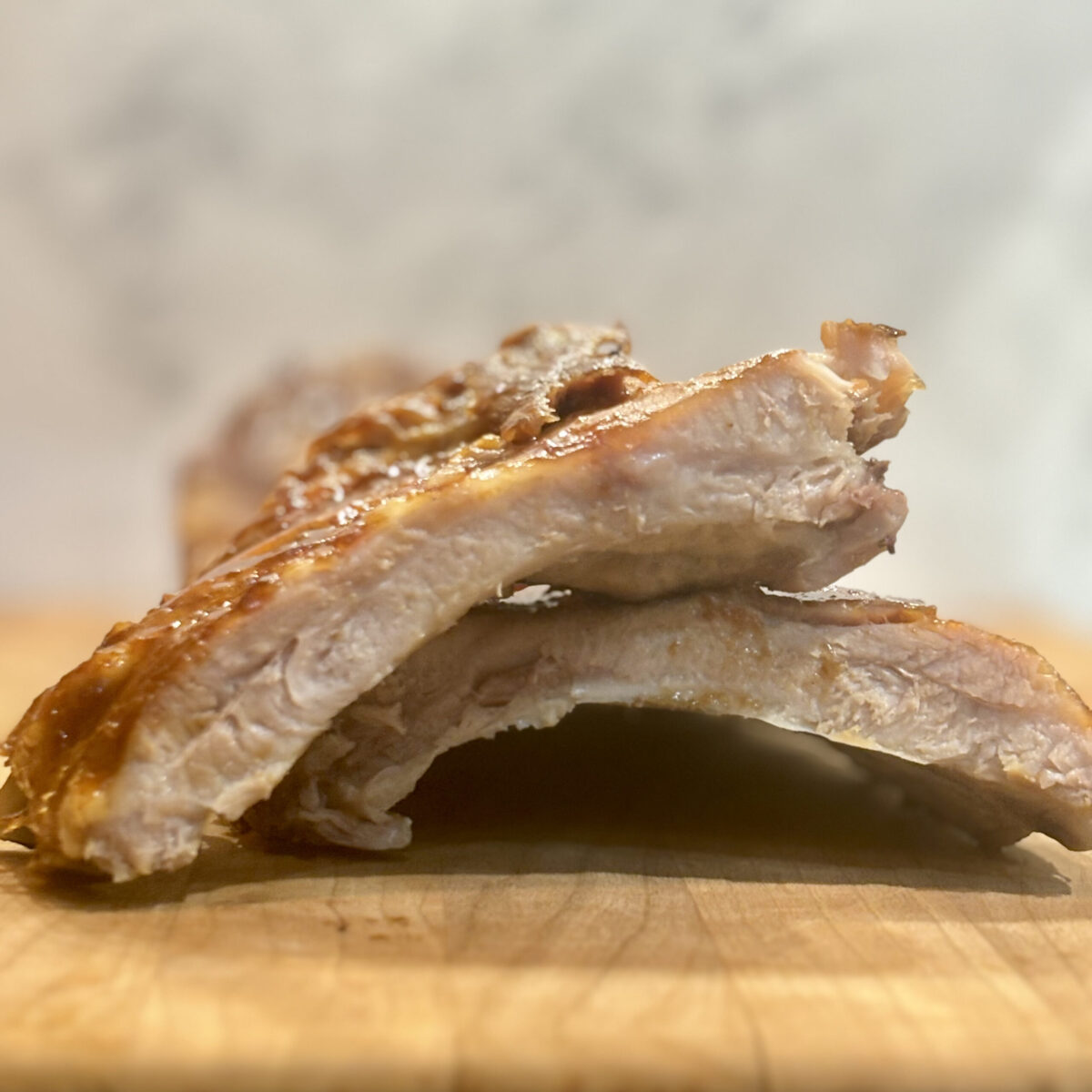 Closeup of a barbecue pork rib lying atop the rest of the rib rack.