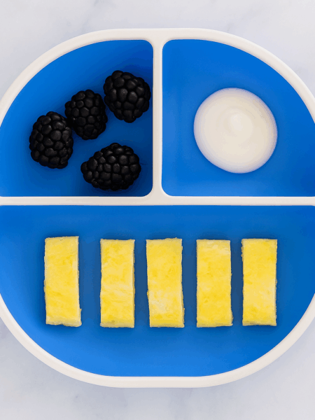 Sliced up baby omelet recipe, accompanied by berries and yogurt.