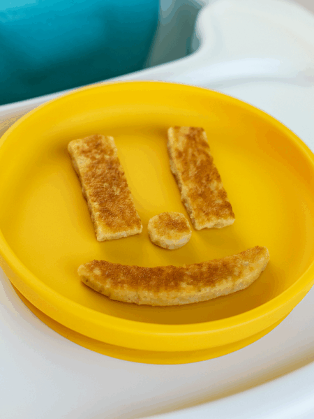 Pieces of banana pancakes for babies starting solids are shaped to resemble a smiley face.