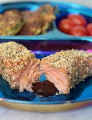 A filet of salmon crusted with crackers and cheese is split in half and fronted by a pool of barbecue sauce.