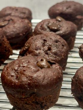 A zoomed-in shot of rows of chocolate beet muffins on a cooling rack.