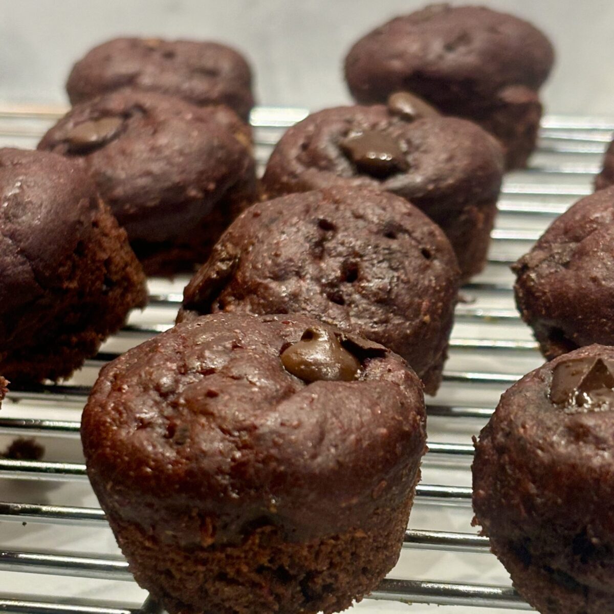 A zoomed-in shot of rows of chocolate beet muffins on a cooling rack.