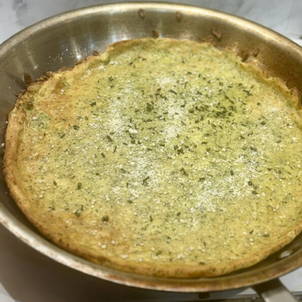 A full dutch baby pancake is presented in pan before cutting.