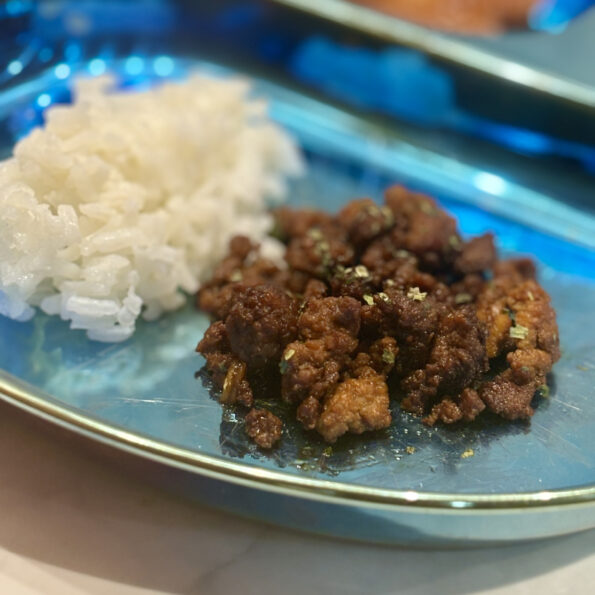 A pile of marinated beef is sided with a mound of rice.