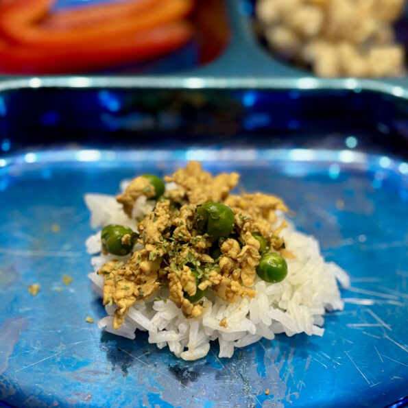 A close-up of a simmered beef and peas dish over rice.