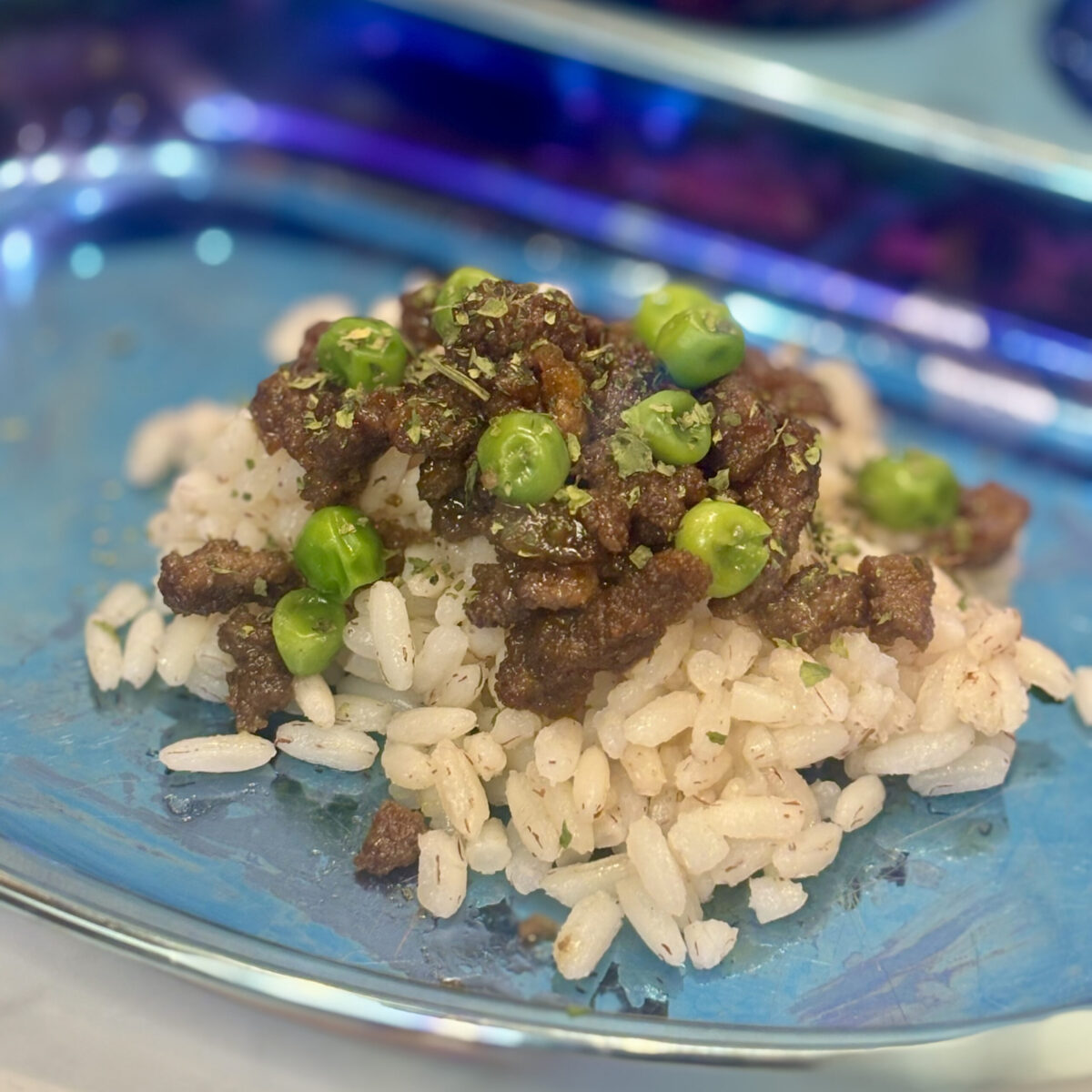 This toddler ground beef recipe shows morsels of marinated beef mixed with peas and placed on top of rice.