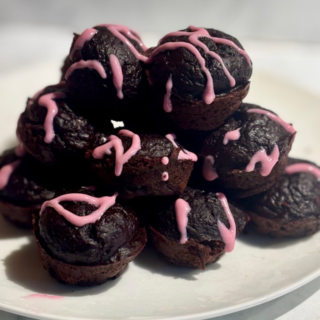 A stack of chocolate beet muffins are shown laced with beet pink frosting.