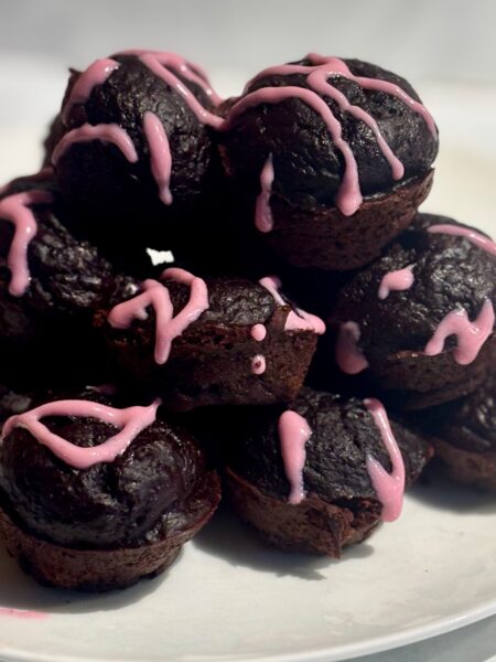 A stack of chocolate beet muffins are shown laced with beet pink frosting.