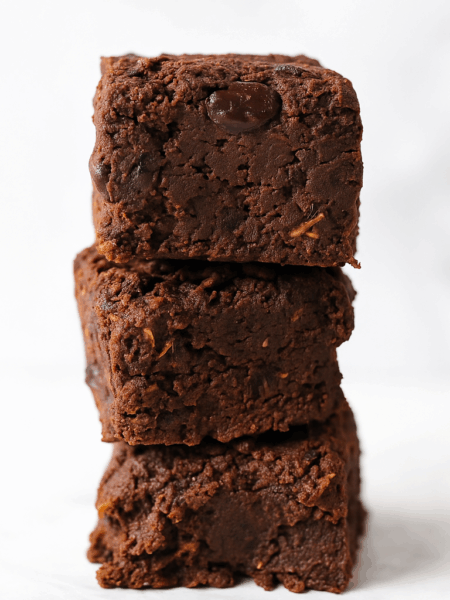 Healthy chocolate brownies, made with sweet potatoes and black beans, are shown stacked on top of one another.