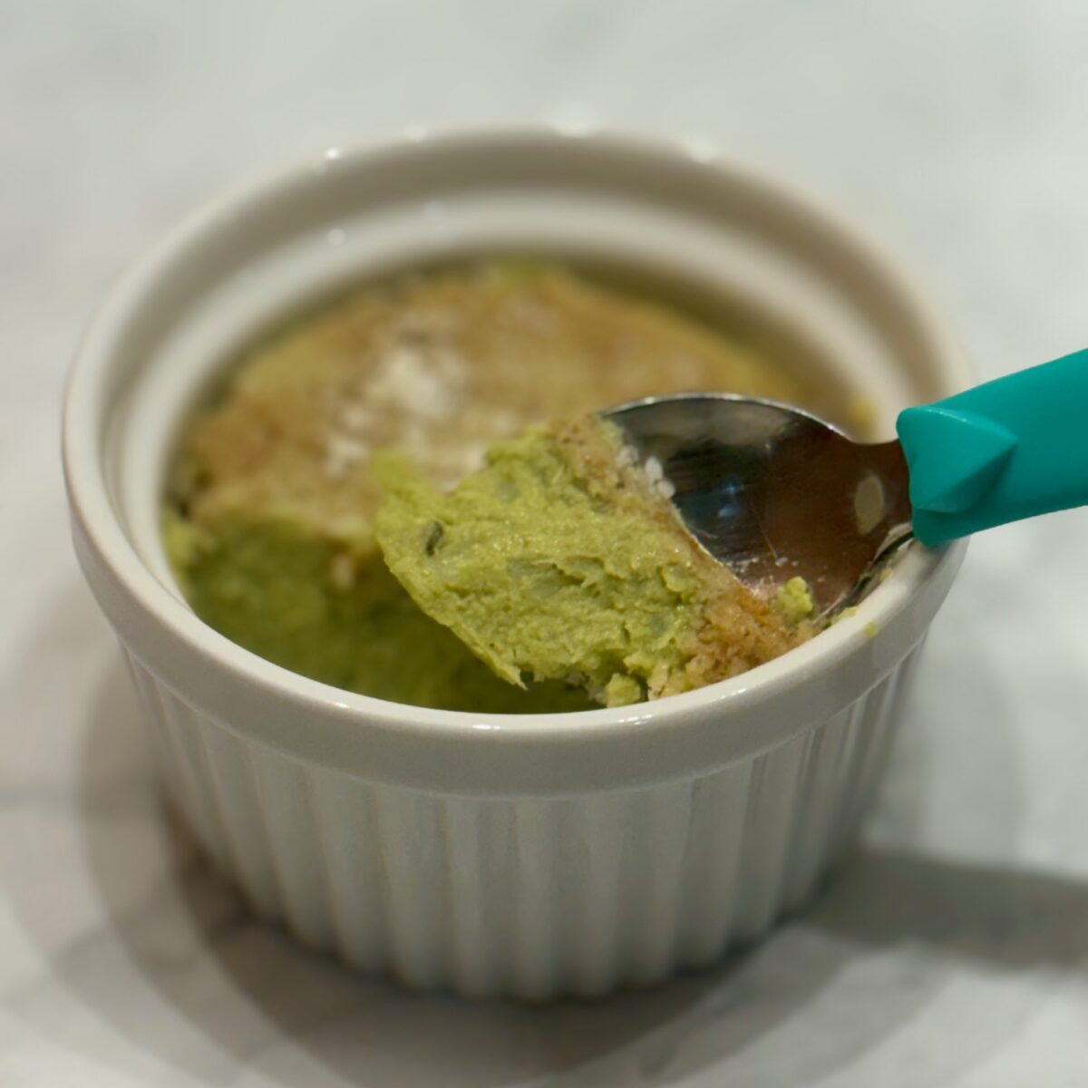 The custardy insides of an asparagus pudding are shown as a spoon scoops up a piece.