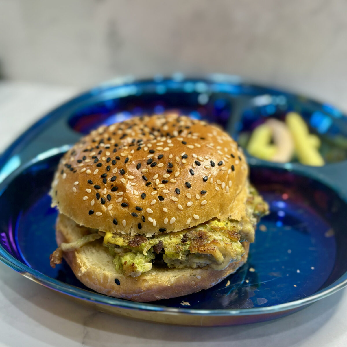 Infant and toddler burger, studded with avocado and black beans, is presented on a bun.