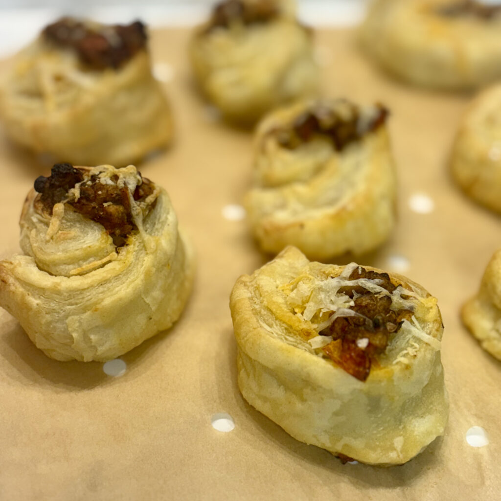 Spirals of toddler eggplant puffs line parchment paper.