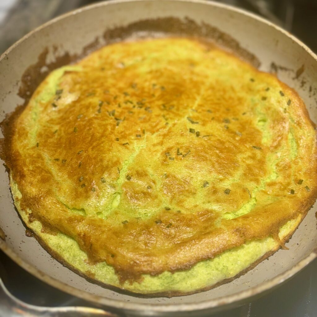 A baked crepe, known as a dutch baby, is shown in the pan in which it was cooked.