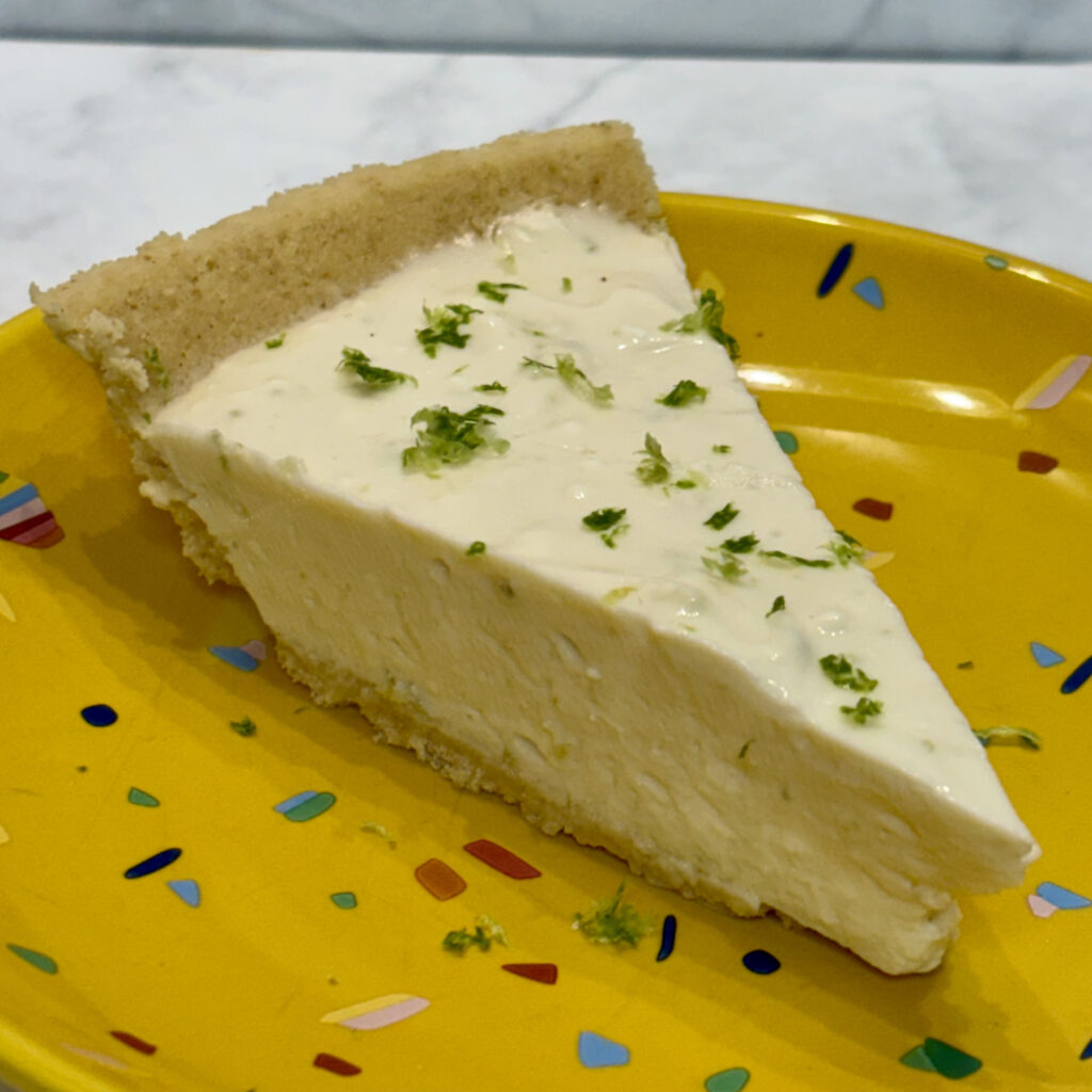 A slice of toddler cheesecake is dusted with lime zest.