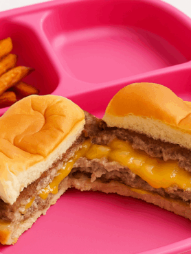 A toddler cheeseburger done in the style of a Juicy Lucy, shown on a plate with sweet potato fries.