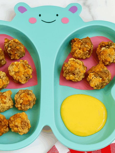 Toddler sausage balls, sided by a pool of honey mustard dipping sauce.