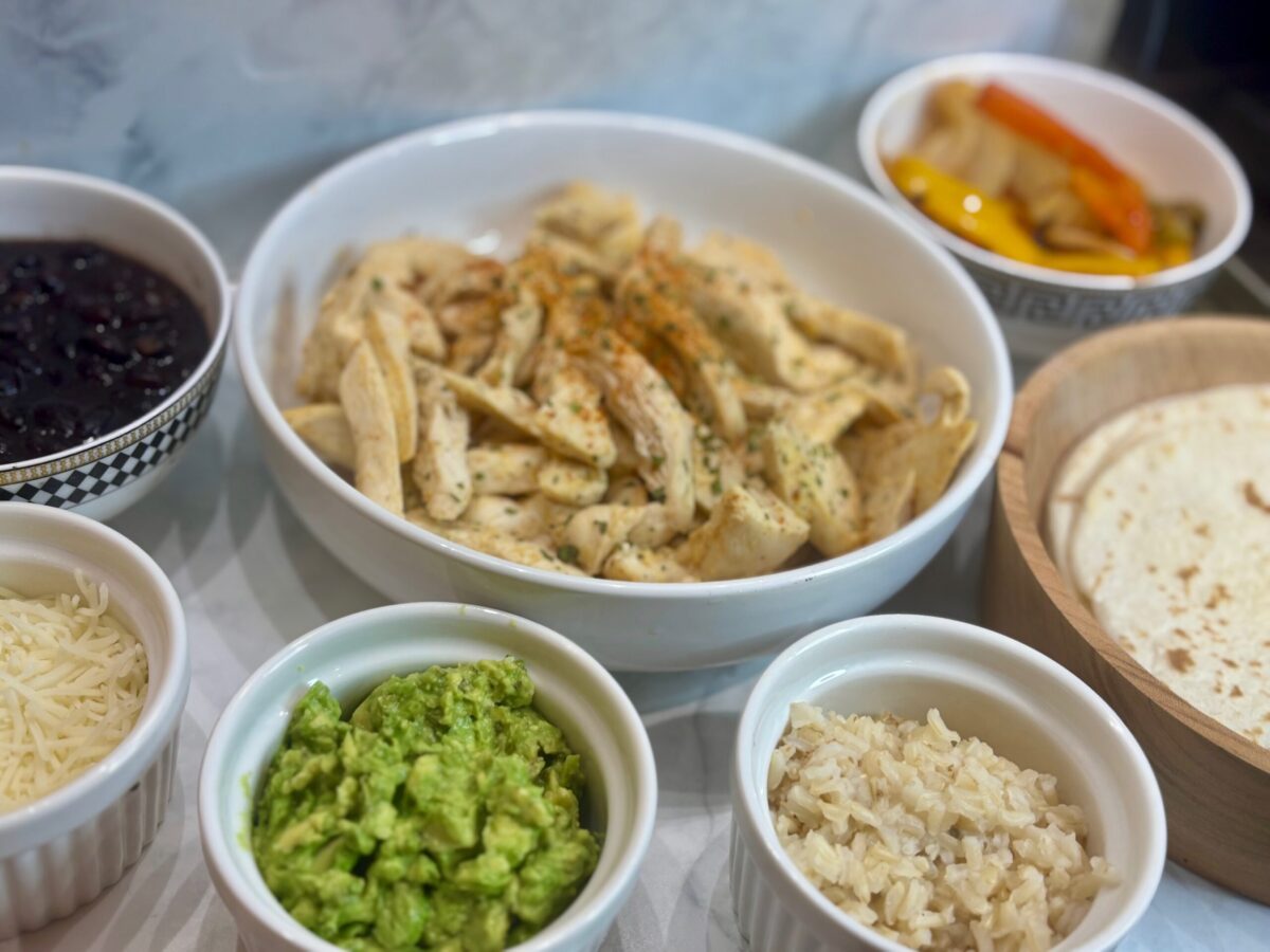 All ingredients and toppings for fajitas for kids on display: chicken, peppers, tortillas, guacamole, beans, etc.