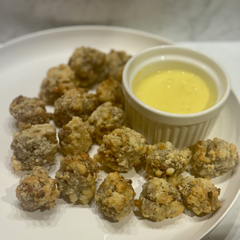 A plate full of toddler sausage balls surrounding a honey mustard sauce.