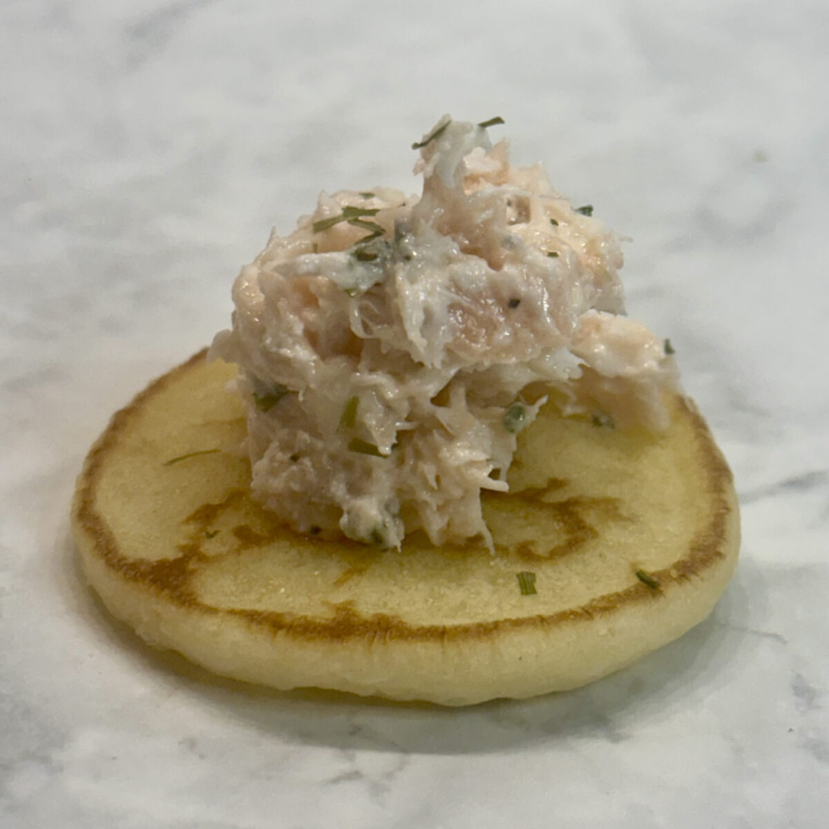 A pile of infant- and toddler-friendly salmon rillettes sits atop a blini.