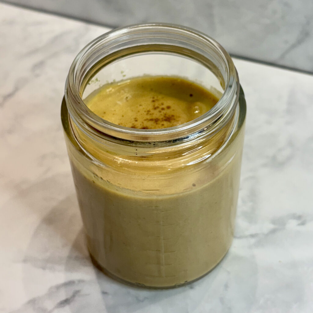 A toddler protein smoothie is presented in a small mason jar, with its top dusted with cinnamon.