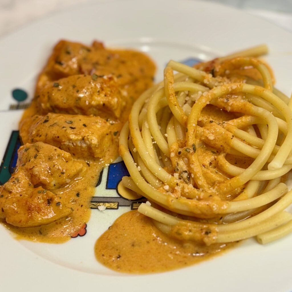 The chicken recipe for kids Marry Me chicken, modified for toddlers, is plated next to spaghetti with the same sauce.