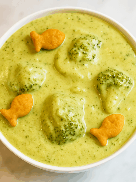 A bowl of broccoli cheddar soup, topped with Goldfish, is shown.