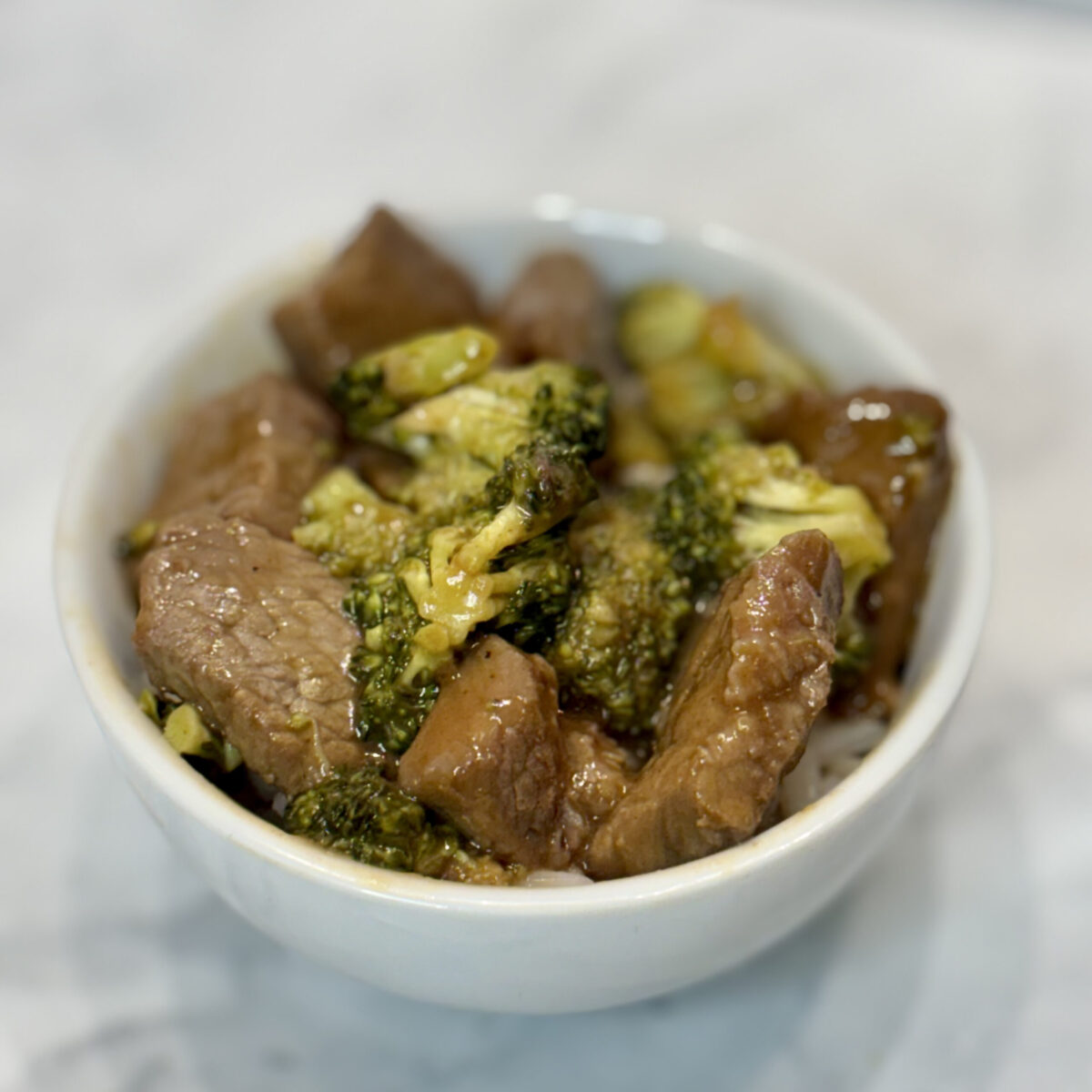 Toddler beef and broccoli is presented atop rice in a small bowl.