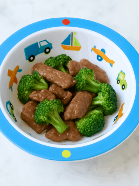 Toddler beef and broccoli presented in a small ramekin, with pieces of steak and broccoli intermingling.
