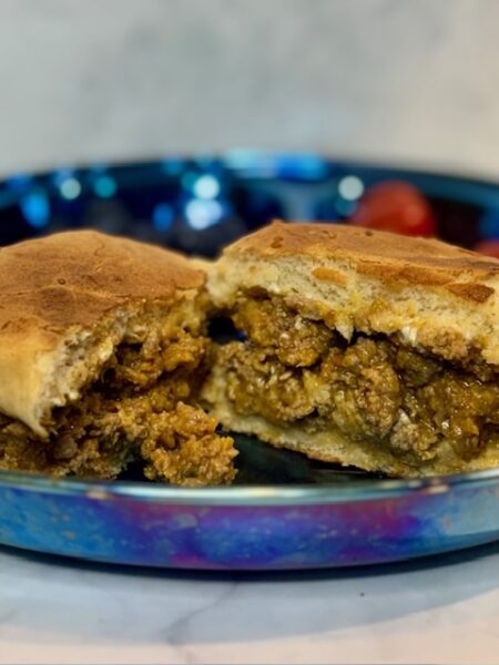 Halves of a sloppy joes for toddlers sandwich are splayed on a plate.