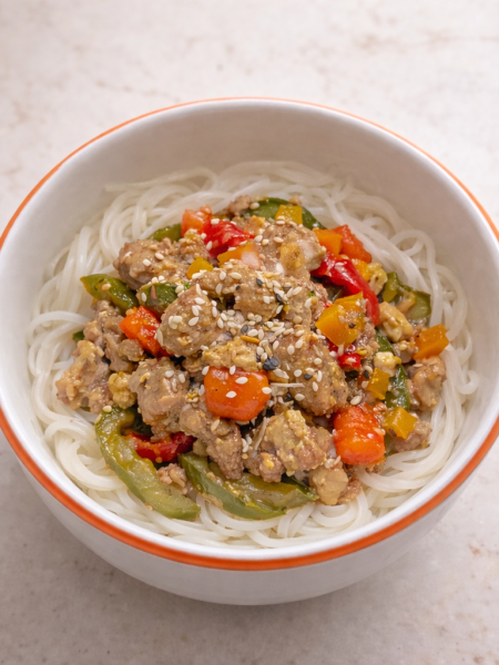 A bowl holds an ideal first stir fry for toddlers: chicken, eggs, celery, onions, and peppers cooked in a light sauce and served over noodles or rice.