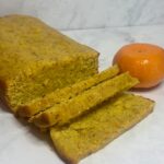 A cake made from leftover clementines is shown in loaf form, with some slices cut.