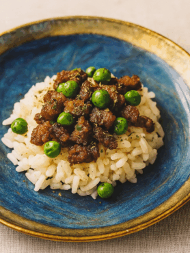 An image of a novel toddler ground beef recipe, here a donburi of marinated ground beef and peas, set over rice.