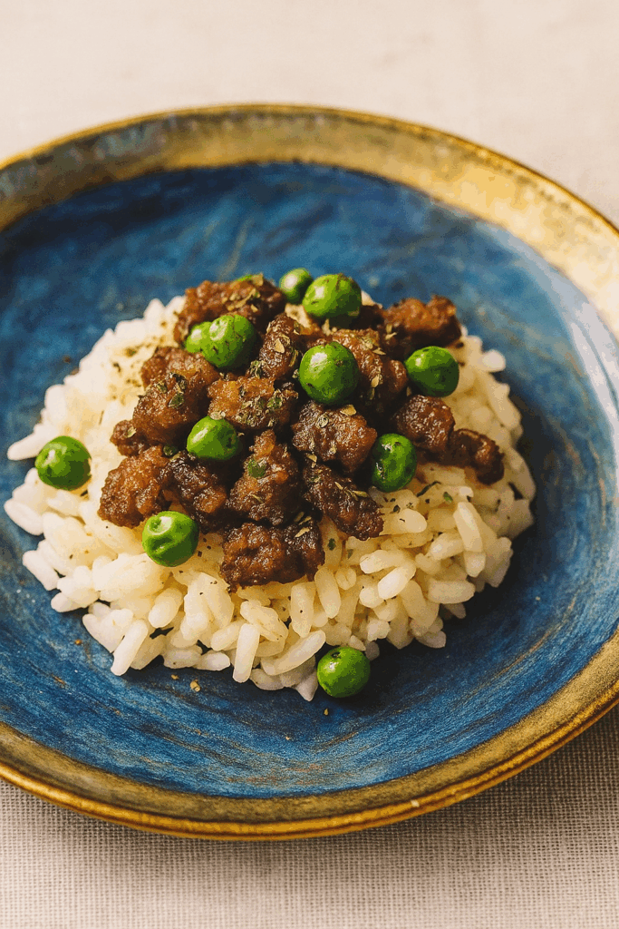An image of a novel toddler ground beef recipe, here a donburi of marinated ground beef and peas, set over rice.