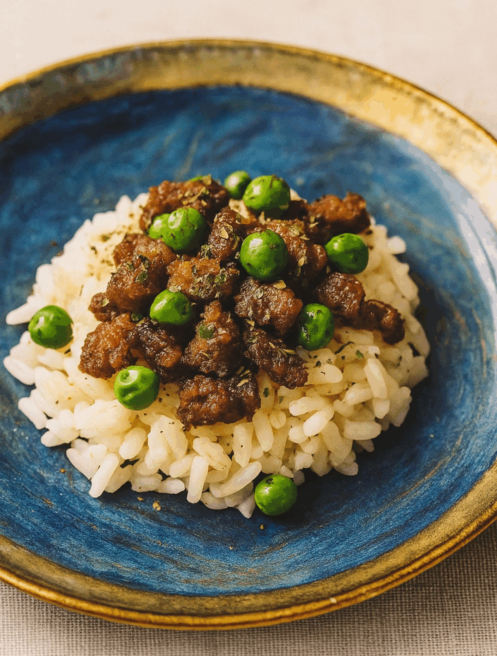 An image of a novel toddler ground beef recipe, here a donburi of marinated ground beef and peas, set over rice.